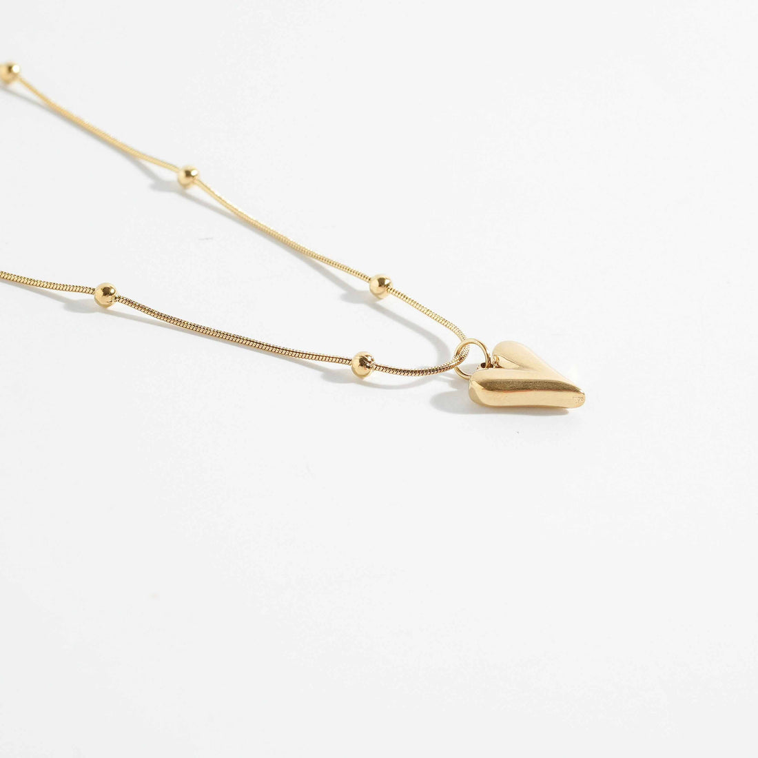 Elegant heart and beads pendant necklace with gold-tone chain. Stylish pendant for women with a modern heart charm, perfect for everyday wear.